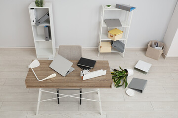 Interior of light office with messy workspace and scattered belongings after earthquake