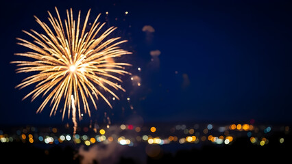 Brilliant golden fireworks exploding in a dark night sky over a city skyline