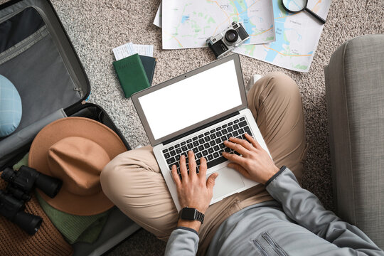 Young male tourist with laptop and map planning his trip at home, top view. Itinerary concept - Powered by Adobe