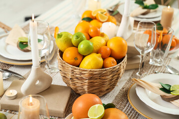 Festive table setting in dining room decorated with citrus fruits. Closeup
