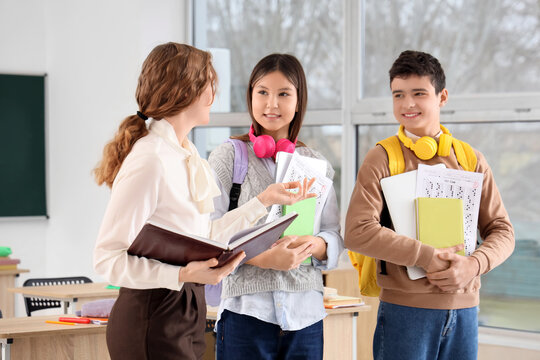 Teenage students with results of school test and teacher in classroom - Powered by Adobe