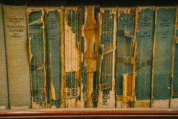 Mumbai, India A row of very old, deteriorating books with torn spines and faded covers. An archival bookshelf documenting the passage of time and historical preservation.