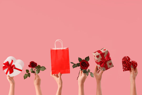 Female hands with roses, gift boxes and shopping bag on pink background. Valentine's Day celebration - Powered by Adobe