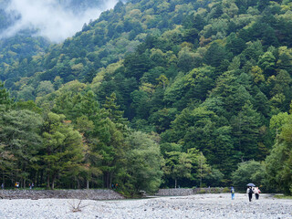 観光名所上高地の梓川の風景と沿岸で散策する観光客の姿