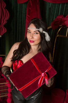A young beautiful woman dressed in gloves stands in a hotel interior and holds a gift