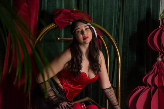 A young beautiful woman, dressed in gloves and retro-style headband-decoration stands near a luggage cart in a hotel interior.