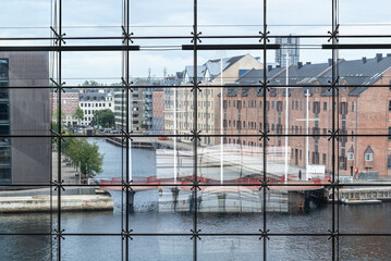 An unrecognizable person on the Cirkelbroen bridge, seen from a large window of the Black Diamond, Copenhague. 