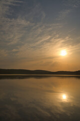 Fototapeta premium Sunset over a calm lake with atmospheric reflections in nature