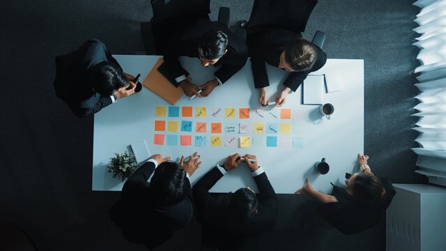 Smart cooperate business people writing and brainstorming business idea by using sticky notes. Top view of diverse project manager sharing marketing strategy on meeting table. Teamwork. Directorate.