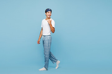 Full body calm young fun man he wear pyjamas jam sleep eye mask rest relax at home point finger...
