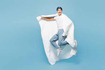 Full body calm young excited man he wearing pyjamas jam sleep eye mask rest relax at home hold duvet blanket run fast isolated on plain pastel light blue cyan background. Good mood night nap concept.