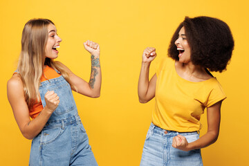 Side view two young happy friends buddies women wear denim casual clothes together do winner...