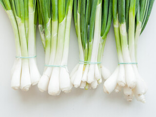 Fresh green leek onion on wooden background, top view bunch of greens on the table.