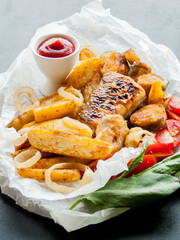 Portion of fish and chips with ketchup sauce, baked potatoes with seafood with vegetables.