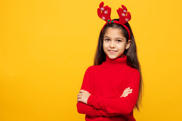 Merry little girl wear red clothes fun decorative deer horns on head posing hold hands crossed folded look camera isolated on plain yellow color background. Happy New Year Christmas holiday concept.