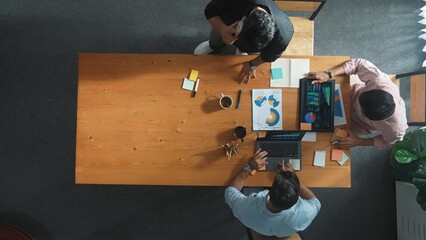 Smart project manager calling phone while diverse team brainstorm idea and looking at financial statistic at tablet at meeting table. Diverse business people planning marketing strategy. Convocation.