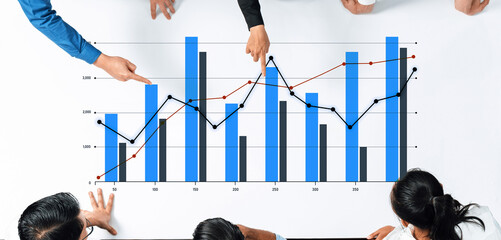 A diverse team engages in analyzing data trends through charts and graphs in a modern workspace, highlighting collaboration and strategic decision-making processes together. Scalp