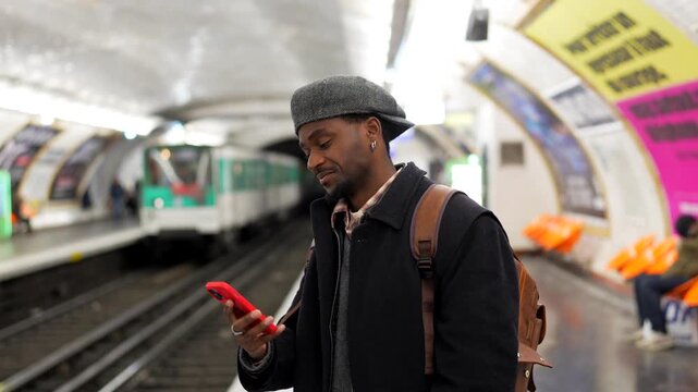 Stylish young black man using smartphone waiting for subway train