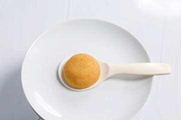 Small round chiffon cake on a white ceramic spoon and plate, minimal style food image suitable for menu use, Top view