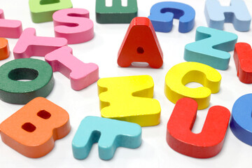 Naklejka premium Colorful wooden English letters scattered on a white background. Perfect for teaching materials, kids learning, language education, and creative design, close-up