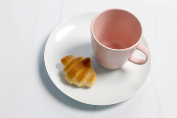 Mini croissant on a white plate with a pink ceramic cup in a minimal style, Coffee time, suitable for food photography and menu use, Top view