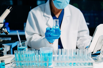 scientists in lab coats conducting research, handling glassware, and working with chemicals in a modern, high tech laboratory.