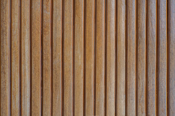 Vertical brown wooden slats texture background. Close up of timber wall panel pattern with natural wood grain detail and linear design.