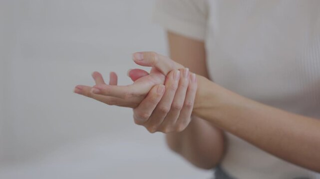 Close-up of a woman holding her wrist in pain, possibly due to carpal tunnel syndrome, repetitive strain, or injury. Concept of hand pain, joint inflammation, or muscle discomfort.