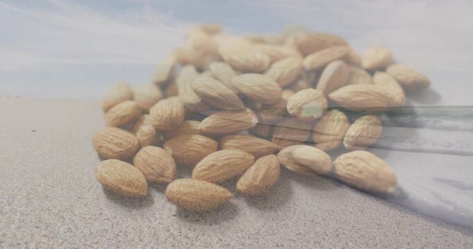 Playback starting, water overlay sweeping across unshelled almonds on sand for food marketing