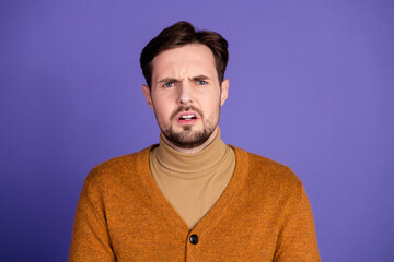Obraz premium Young man with orange cardigan looks surprised against purple background in casual fashion style
