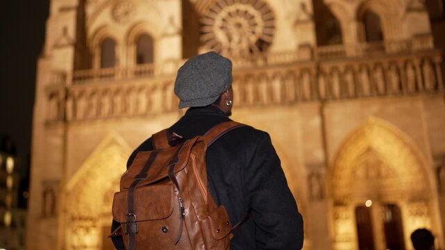 Black tourist admiring notre dame cathedral at night