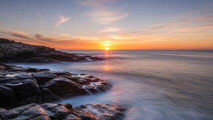 Golden hour illuminates a dramatic rocky coast as long exposure smooths the tranquil ocean waves.