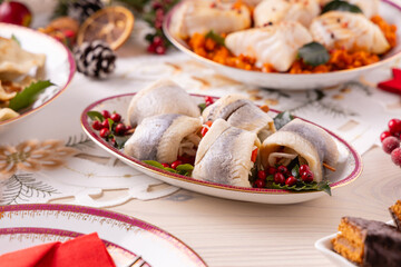Classic Christmas food medley on a decorated table. Fish, dumplings stuffed with cabbage and mushrooms, cheesecake, and ham.