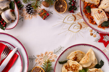 Classic Christmas food medley on a decorated table. Fish, dumplings stuffed with cabbage and mushrooms, cheesecake, and ham.