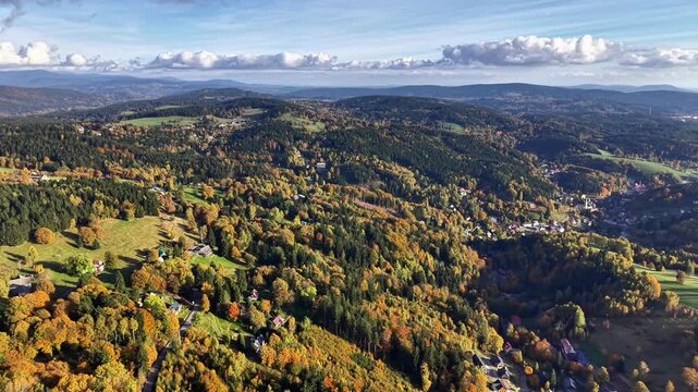 aerial hillside mosaic of autumn villages and mixed forest, colorful patchwork of houses, fields and winding