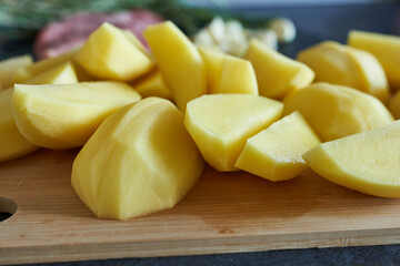 Raw potatoes on wooden cutting board, close-up, selective focus