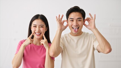 Happy young asian couple making funny silly faces together. Playful man and woman joking and having fun on a white background. Positive relationship concept with copy space