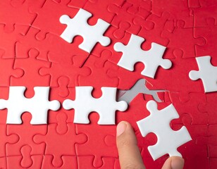 Hand completing white puzzle pieces against a red puzzle background, symbolizing completion