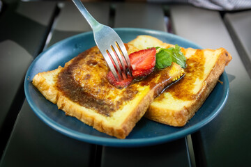 Fork Cutting Strawberry on Sweet French Toast Slices