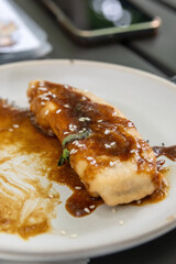 Extreme Close-up of Single Pisang Goreng with Rich Caramel Sauce and Sesame Seeds