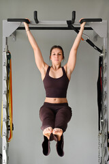 Young woman performing hanging leg raise exercise