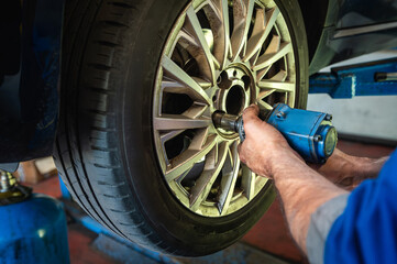 Mechanic changing car wheel in workshop garage