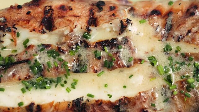 Grilled monkfish served in a restaurant with a creamy garlic sauce and greens.
