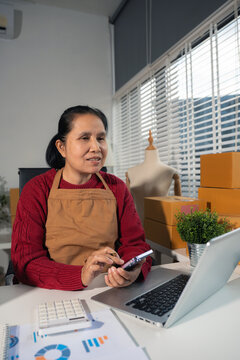 Startup small business entrepreneur or freelance using a laptop with box, checking orders from customers, matron runs an e-commerce business on websites and social media. 