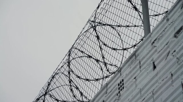 Security systems restricted area. Sharp razor blades on barbed wire. Prison wall.