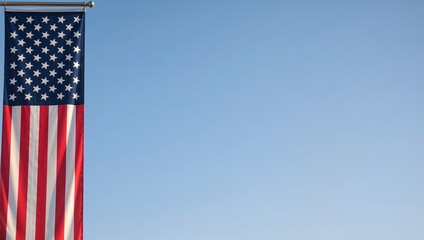 Stars and stripes hang vertically on a golden pole against a clear blue sky, patriotism, freedom, sunny day