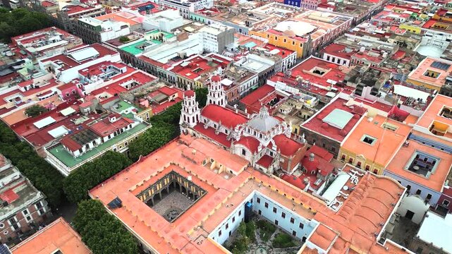 Aerial establishing over Puebla rooftops showing dense colorful blocks, cathedral detailed architecture