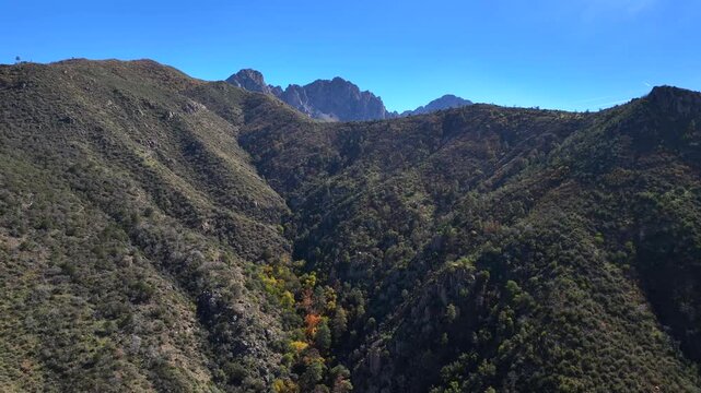 Aerial view of rugged Four Peaks Wilderness, a tapestry of green and brown vegetation under a clear blue sky, Apache Junction, Arizona, United States.