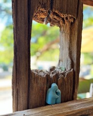Ceramic figurines framed by weathered wood. Blue ceramic figurines nestled inside a weathered...