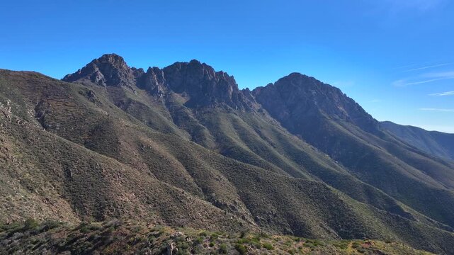 Aerial view of the rugged Four Peaks Wilderness, where sun-kissed slopes meet the azure sky, creating a striking contrast of light and shadow, Apache Junction, Arizona, United States.